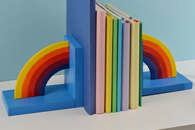Zwei regenbogenförmige Buchstützen halten Bücher.